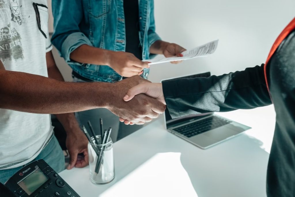 A Courtesy Cash representative shaking hands with a customer across a desk after approving a loan